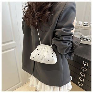 Chic white pleated bucket bag with black floral embroidery on a street style model