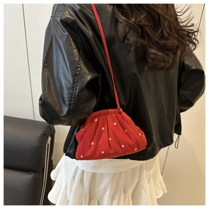 Detailed view of red pleated bucket bag with small white flower prints and textile texture
