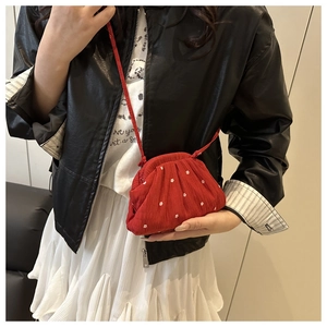 Detail of red pleated fabric shoulder bag with white floral embroidery and cord strap