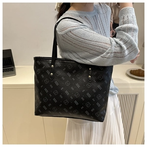 Detail of black tote bag with printed bear patterns and textured lychee leather finish