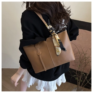 Brown matte leather tote bag detail with decorative printed scarf and white stitching