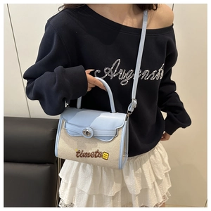 Dettaglio di una borsa a tracolla bicolore con ricamo e cinturino su una modella