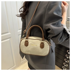 Détail du sac bandoulière en toile et cuir marron porté par un mannequin en costume gris