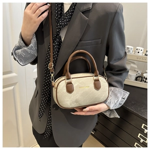 Détail d'un sac Boston en toile beige et cuir marron porté par un mannequin élégant
