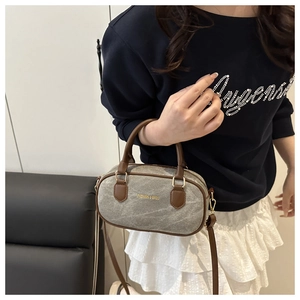 Détail du sac Boston en toile grise avec poignées en cuir marron et boucles dorées
