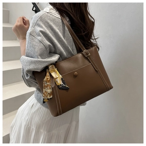Dettaglio borsa tote marrone scuro con cuciture bianche e foulard floreale sul manico