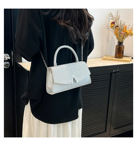 Detail of silver crossbody bag with glitter texture, V-shaped buckle, and metal chain