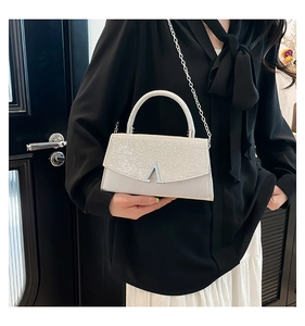 Detail of silver sequin handbag showing flap with metal logo and chain strap on model