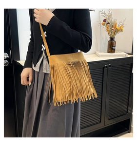 Close-up of retro ginger yellow suede shoulder bag with long bohemian tassels decoration