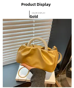 Detailed shot of golden pleated cloud bag with elegant pearl handle and fine shoulder strap
