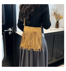 Detail of yellow matte PU crossbody bag featuring bohemian long fringe and slim strap