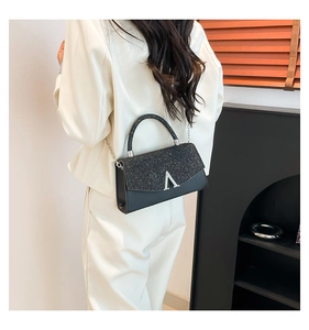 Rear view of model wearing a black sequined crossbody mini bag with silver V buckle