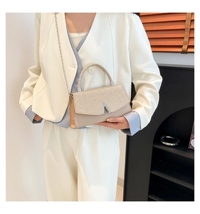 Détail de la finition pailletée or champagne et du fermoir argenté en V sur le sac