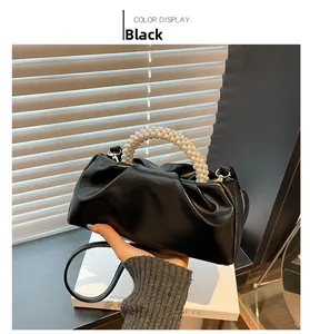 Detail of black pleated cloud bag with elegant pearl handle and leather strap