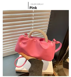 Detail of pink pleated cloud bag featuring elegant pearl top handle and slim shoulder strap