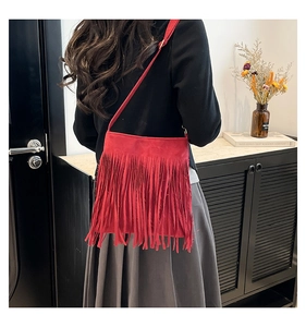 Détail d'un sac à bandoulière rouge à franges en daim porté par un mannequin femme