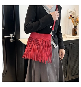 Detail of red tassel shoulder bag with adjustable leather strap and gold metal hardware