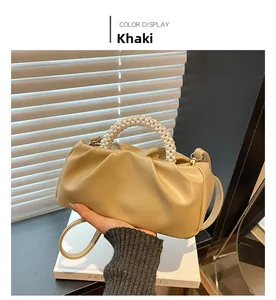 Detail of khaki cloud bag with pearl woven handle and soft pleats in natural light