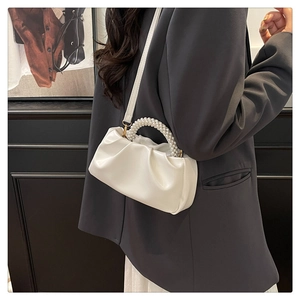 Detailed view of white pleated cloud bag featuring elegant pearl handle and PU leather strap