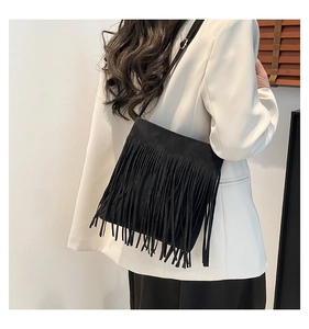 Close-up of black matte PU leather shoulder bag featuring long fringe and thin strap details