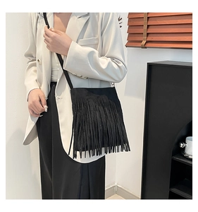 Model wearing a black tassel crossbody bag with matte finish and long fringe details