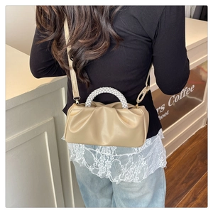 Detail of pleated beige cloud bag with elegant pearl bead handle and leather strap