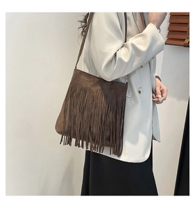 Brown faux suede shoulder bag with long fringe tassels shown on model with a white blazer