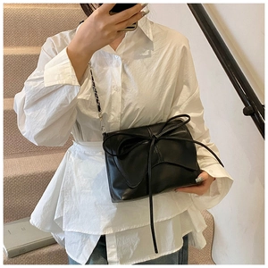 Detail van de zwarte crossbodytas in balletstijl met strik en metalen kettingriem