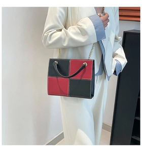 Detail of red and black checkered crossbody bag with gold chain and white stitching