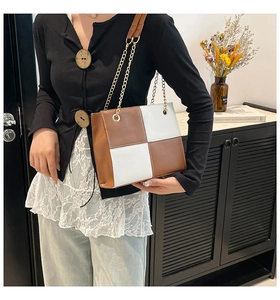 Detail view of brown and white color-block square crossbody bag with gold chain strap