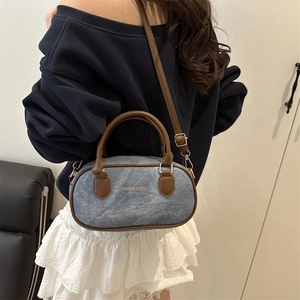 Mini sac Boston en denim avec garniture en cuir marron porté par un mannequin
