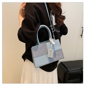 Détail du sac à main patchwork bleu et gris avec texture fine et étiquette tendance