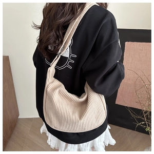 Detail of a large cream corduroy crescent bag shown on shoulder in a cozy setting