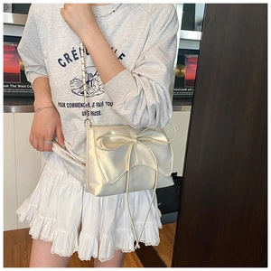Detail van de parelmoer ballet-stijl crossbody tas met grote strik en metalen ketting