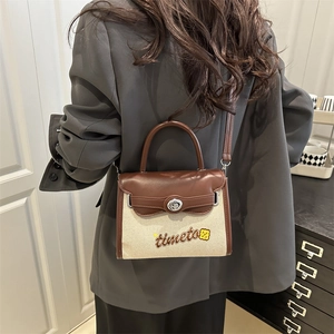 Borsa a tracolla retrò in tela con finiture in pelle e ricami su un blazer grigio