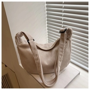 Detail of beige corduroy crescent bag showing soft ribbed texture and adjustable strap