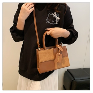 Close-up of brown patchwork leather handbag featuring textured finish and fashion tag