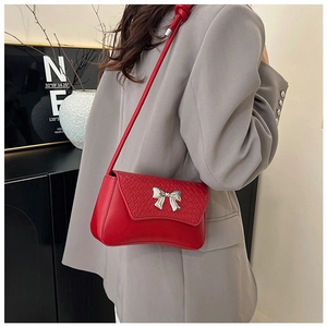 Detail showing the red faux leather surface with crocodile pattern and silver bow buckle