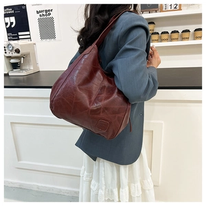 Close-up of deep red tote bag with vintage embossed texture and stylish logo patch