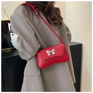 Detail of red crocodile-patterned flap and silver bow buckle on chic baguette bag