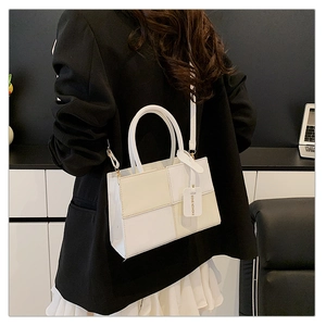 Detail view of stitched contrast panel handbag with fashion tag and leather strap