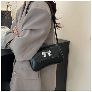Detailed view of crocodile embossed leather handbag with silver bow metal buckle on a model