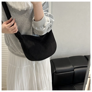 Detail of black corduroy hobo bag showing ribbed texture and wide strap on model