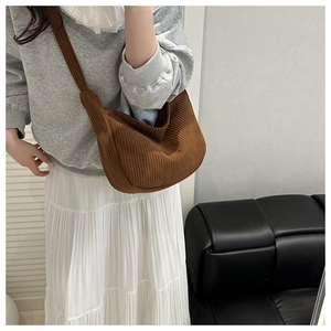 Detailed texture of brown corduroy crossbody bag worn by a model in casual style