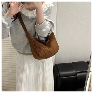 Detail of soft brown corduroy texture on a half-moon hobo bag styled with a casual outfit