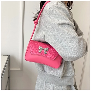 Detailed view of magenta textured shoulder bag with silver metallic bow buckle accent