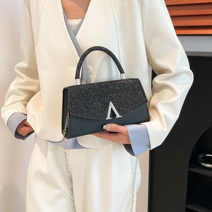 Sac à main noir élégant avec rabat à paillettes et boucle en V sur mannequin chic