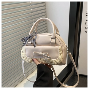 Detail of beige Boston bag featuring lace edges, a leather bow, and checkered silk scarf