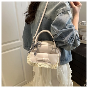 Detail of a beige shell handbag with lace trim and bow knot on a home background