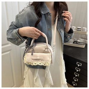 Detail showing the lace trim and ribbon bow on the cream Boston handbag